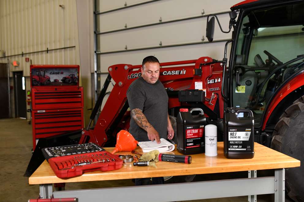 Service technician reviewing manual while working on a tractor