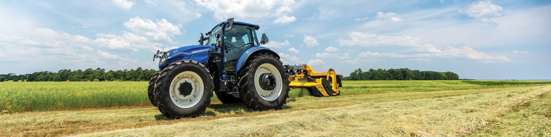 Blue tractor puller mower in a field.