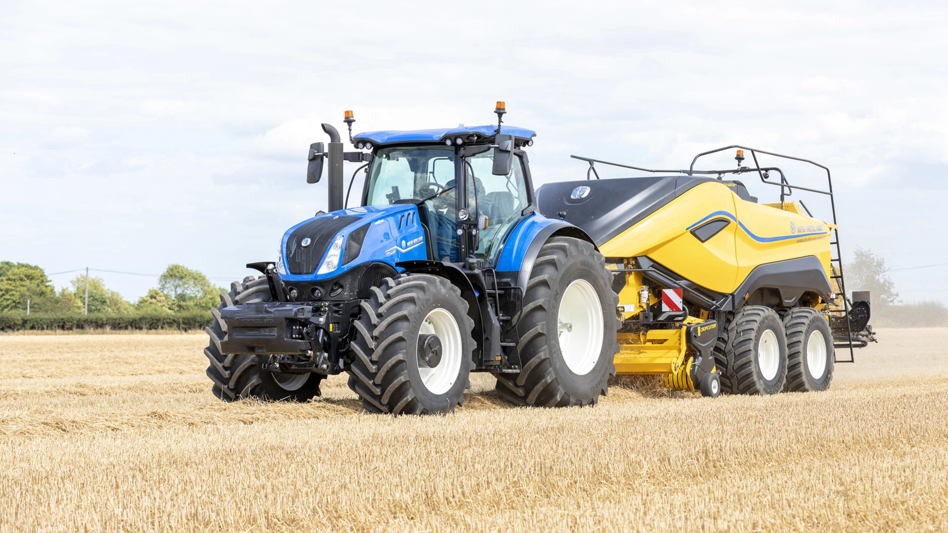 Tractor in action, operating a Bigbaler High Density on an expansive agricultural field