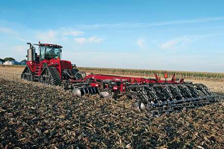 Ecolo-Tiger 875 in a field with a Steiger tractor pulling it.