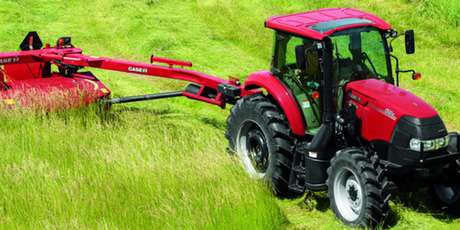 A Case IH Farmall Large Utility 100A Pro Series tractor pulling a Case IH disc mower-conditioner through a field of tall grass.
