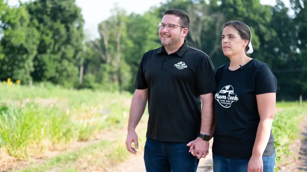 A couple holds hands in a field.