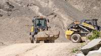 Compact wheel loader and skid steer loader lifting rocks.