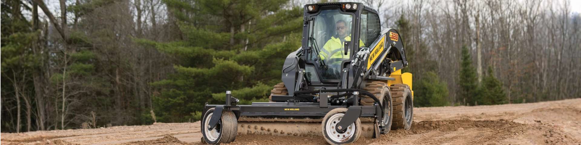 Skid steer loader grading dirt.