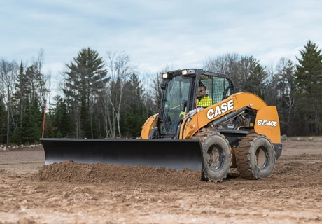 CASE skid steer with a dozer blade attachment moves dirt