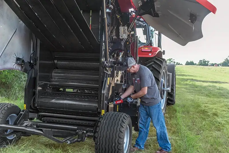 technician lubricating RB465 round baler