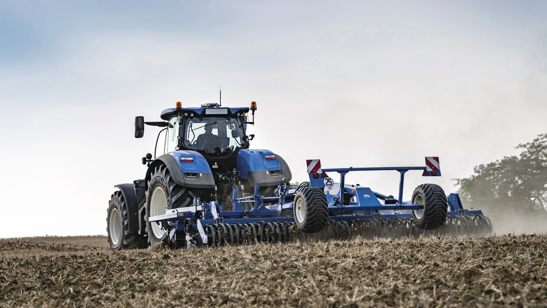New Holland tractor employing a mounted stubble cultivator on the field
