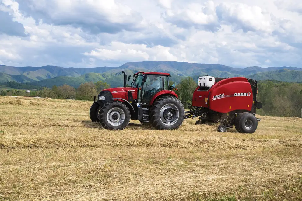 Farmall 140A and Round Baler RB465 with hills in background