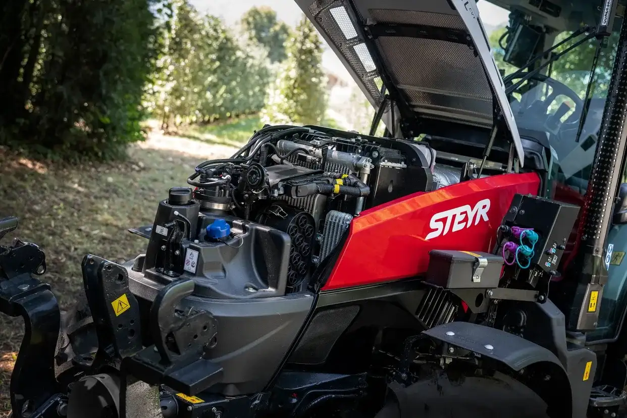 STEYR Spezial Obstbautraktor mit geöffneter Motorhaube und sichtbarem Motor in einer Obstanlage