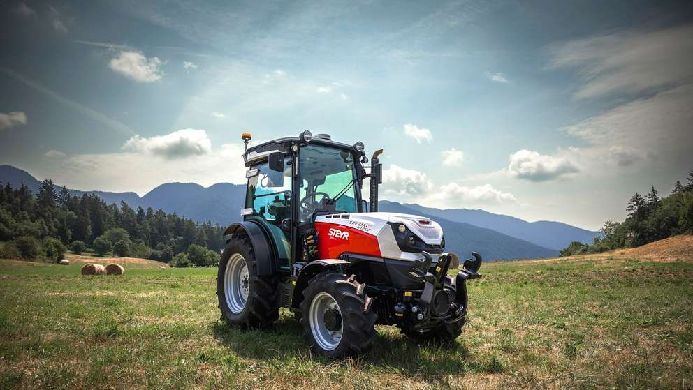 STEYR Spezial 4120F orchard tractor parked in a mountain meadow under a dramatic sky