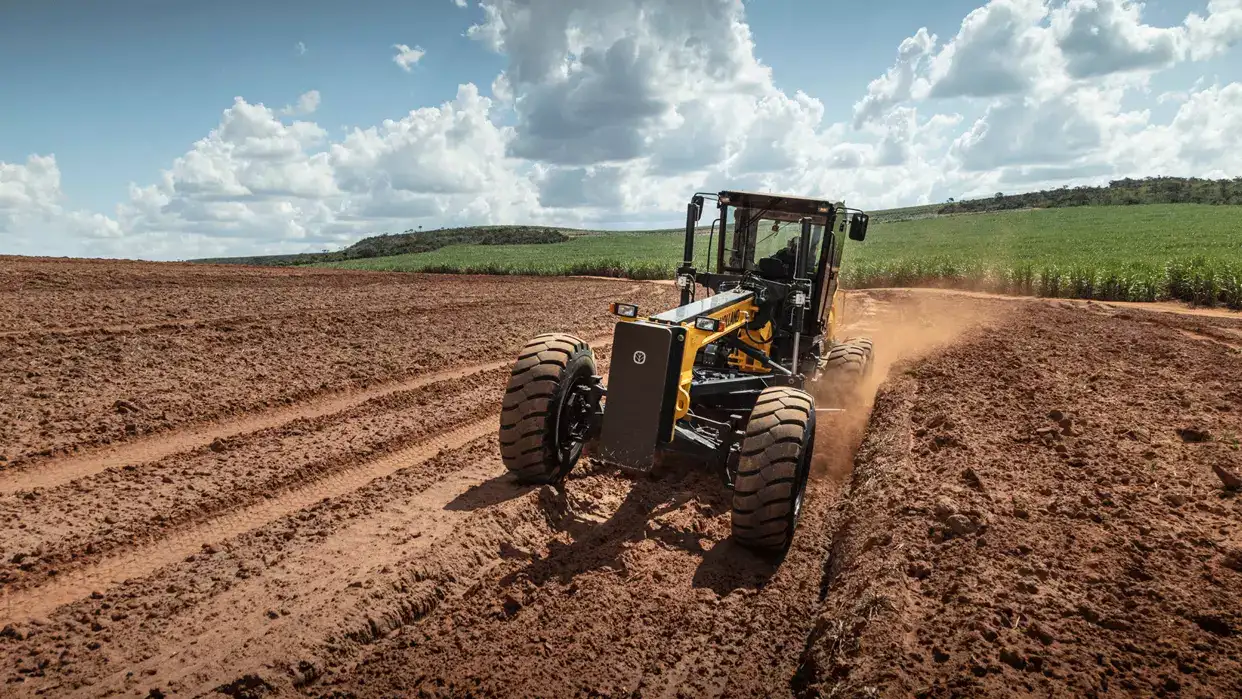 foto ao ar livre da Motoniveladora New Holland Construction, em operação, levantando poeira.