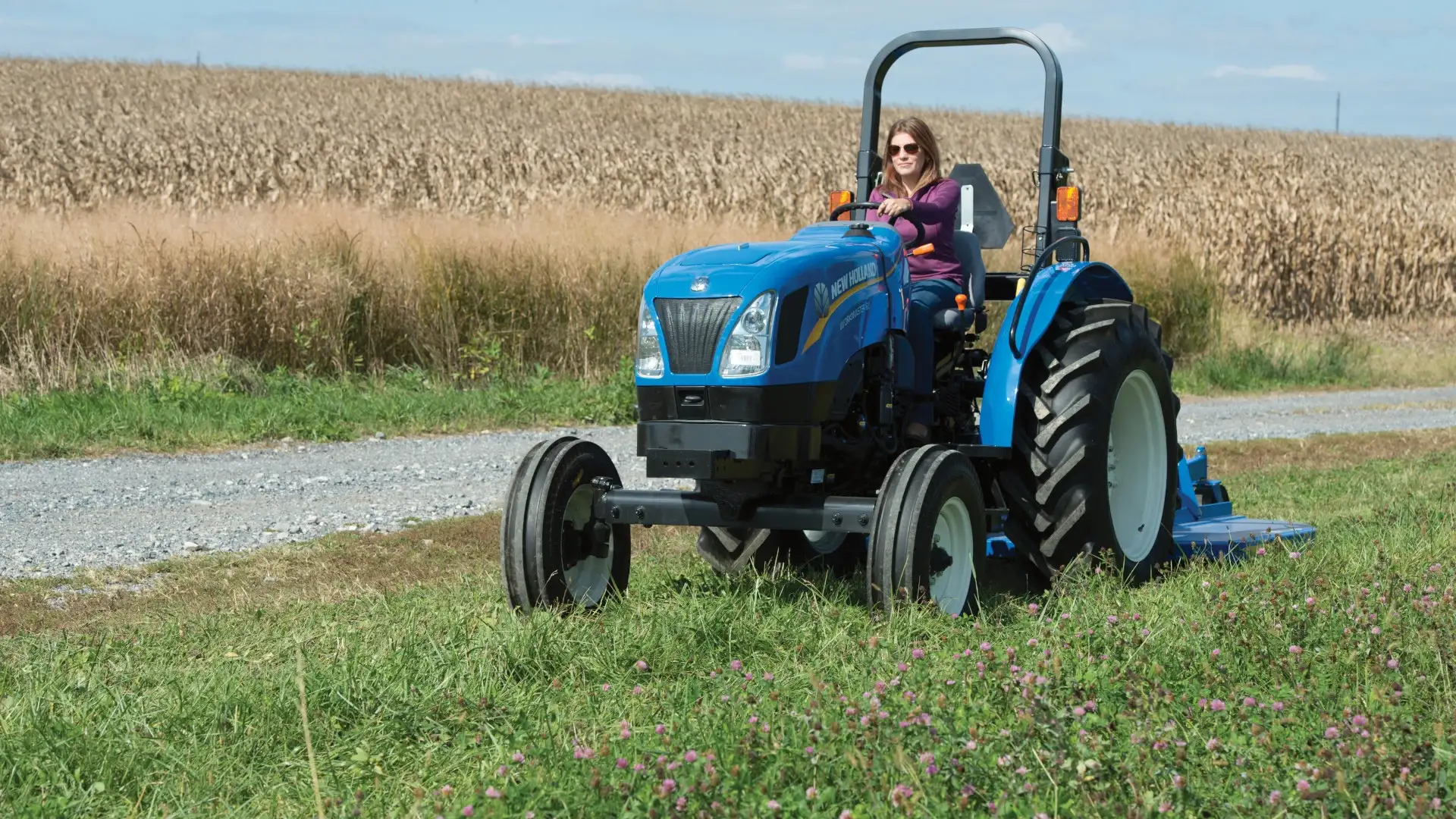 Woman operates WORKMASTER tractor with a mowing implement