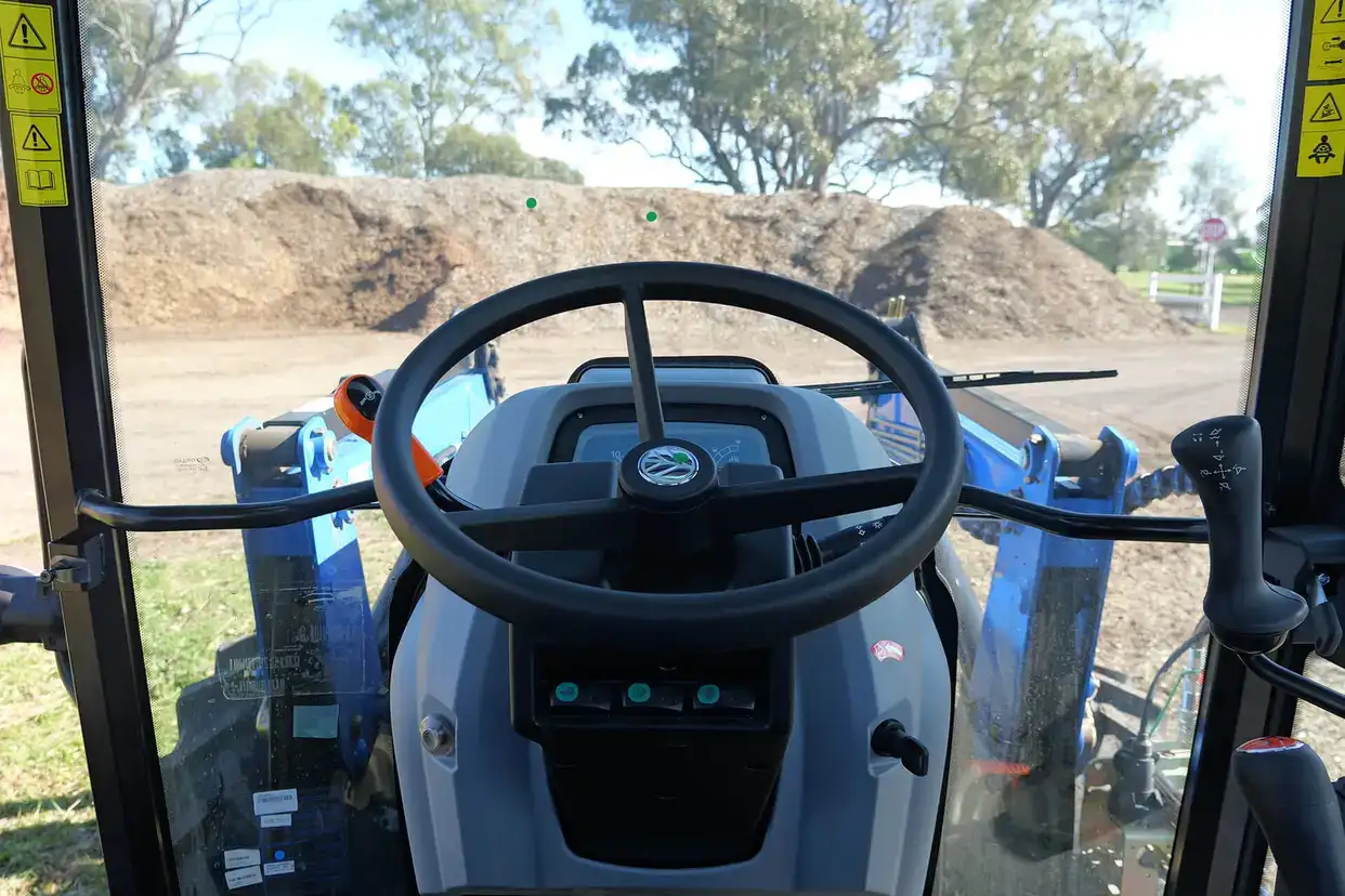 Blue New Holland TT4 Tier 3 tractor in field with loader and 4 in 1 bucket attached