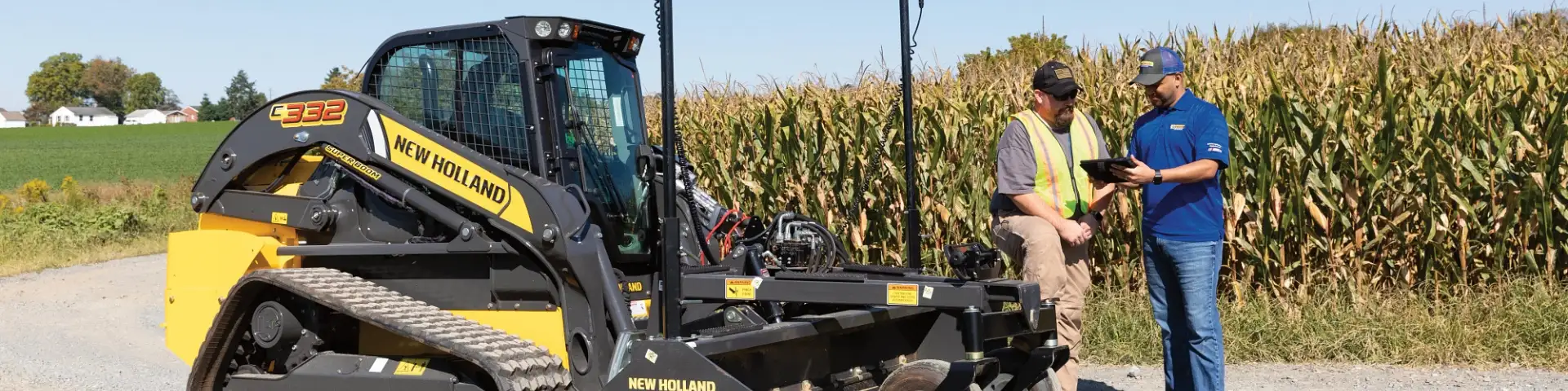 Men look at a tablet together next to a New Holland CTL