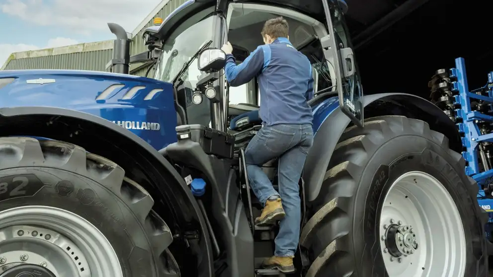 Man climbs up ladder into a tractor cab