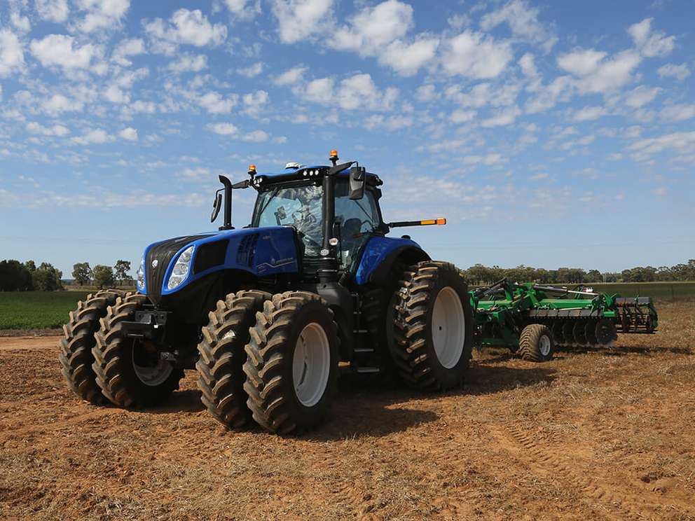 Blue New Holland T8 tractor working in field with K-Line attachment