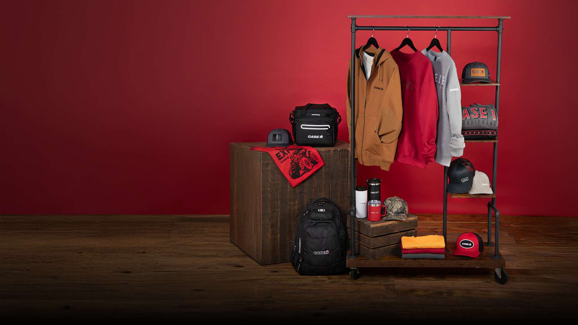 A collection of Case IH branded apparel and accessories against a vibrant red background. Items include hoodies, caps, a backpack, and a water bottle.