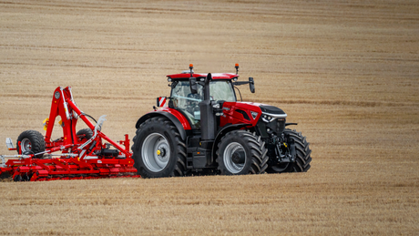 Red Case IH tractor working in a field with a red tillage implement.