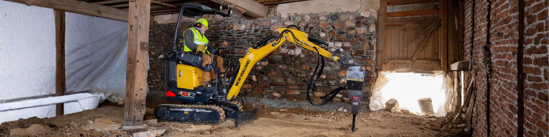 Mini excavator breaking ground with hammer attachment.