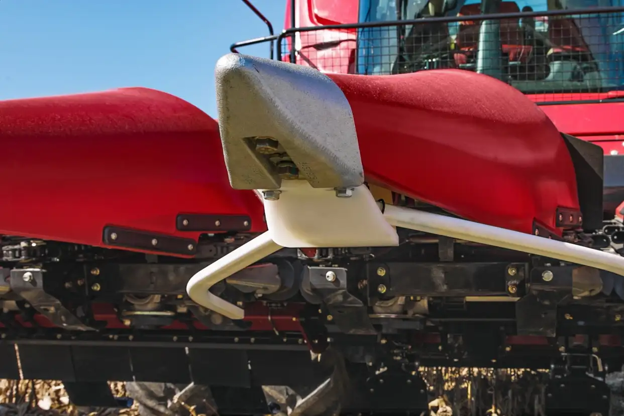 Close-up of a Case IH combine harvester C500 series part, showcasing metal and plastic components under a clear blue sky. Industrial and sturdy.
