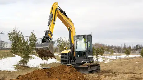 Mini excavator digging in a field.