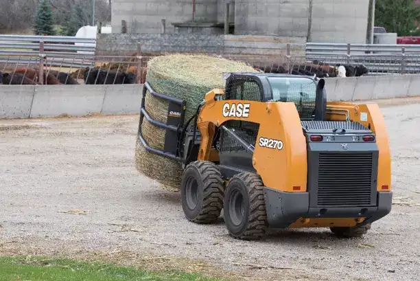 A Case skid steer hauling a hay bail