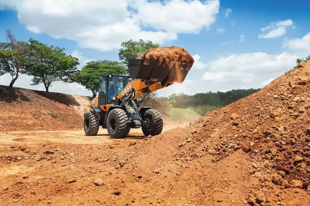 foto ao ar livre da pá-carregadeira da Case fazendo o transporte de material.