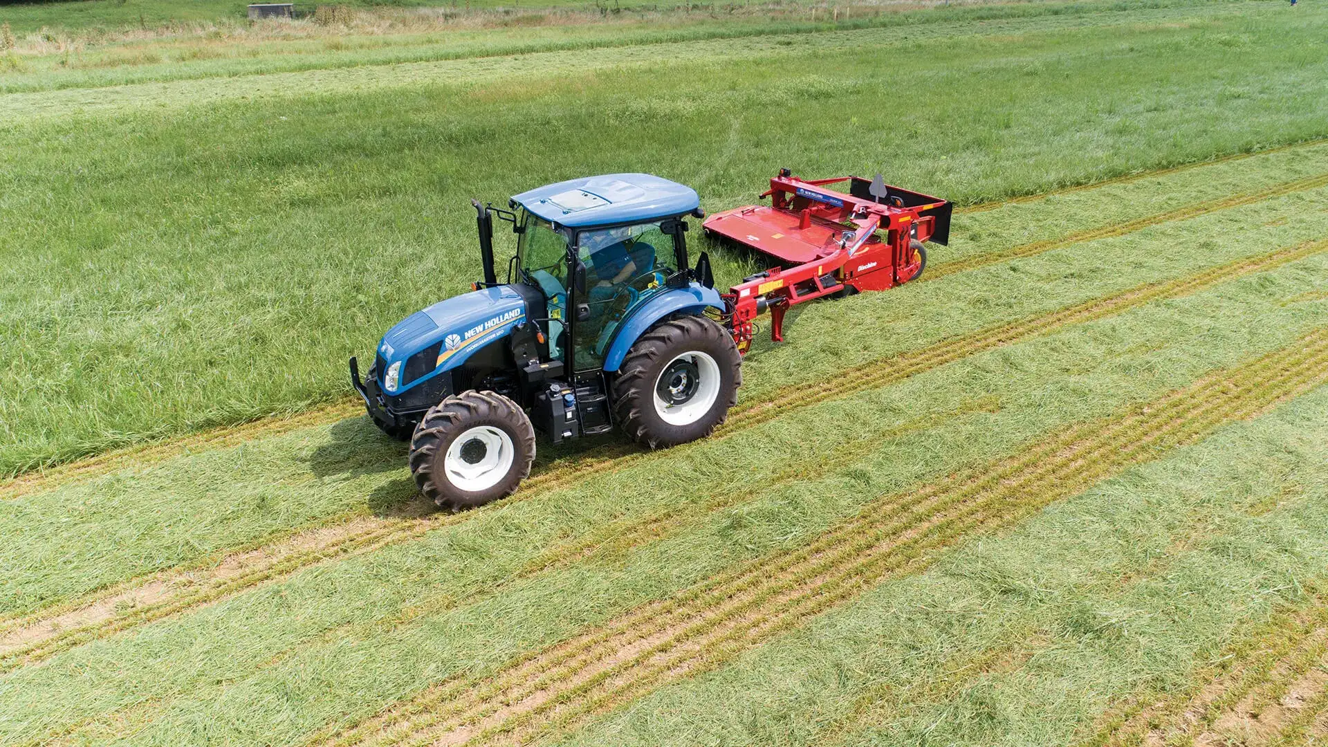 Tractor pulls a Discbine® Side-Pull Disc Mower-Conditioner in the field