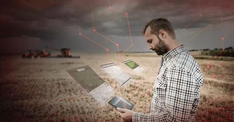 armer in a checked shirt using a tablet in a field, with digital screens and red connection lines overlaid and combine harvesters in the background