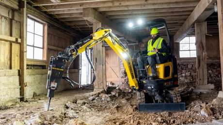 E15X mini excavator breaking concrete with hammer.
