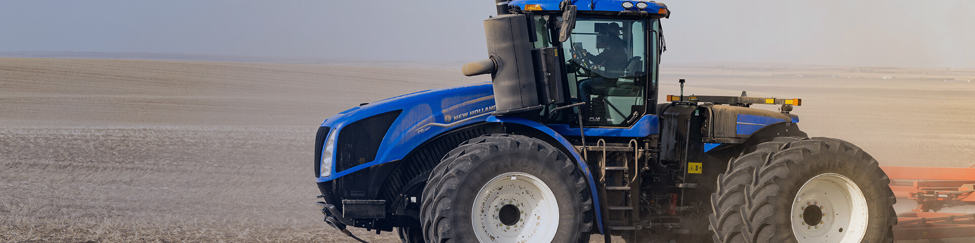 New Holland T9 wheeled tractor, working in field towing implement