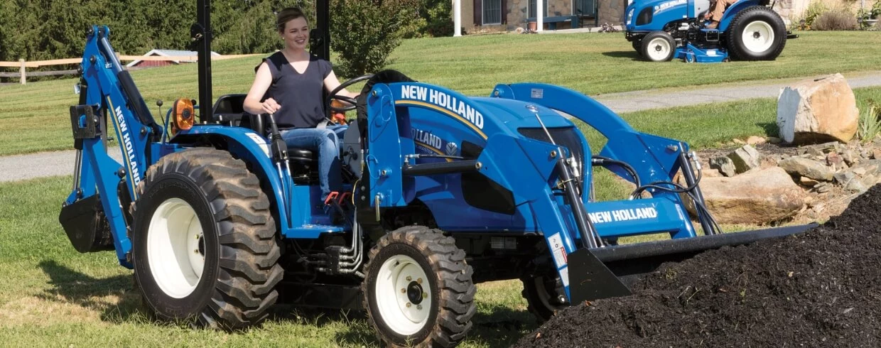 Woman operates WORKMASTER compact tractor with a front loader