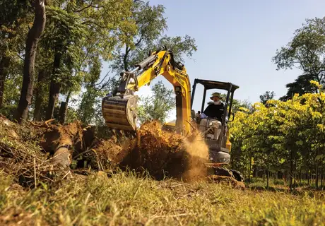 Operator uses excavator with bucket to move materials.