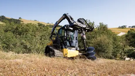 New Holland Construction compact track loader drilling with and auger in a field.