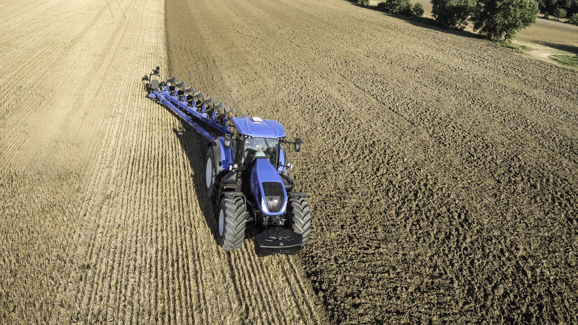 Tractor with 8 Furrow Semi-Mounted Variable Width Reversible Plough working on the field
