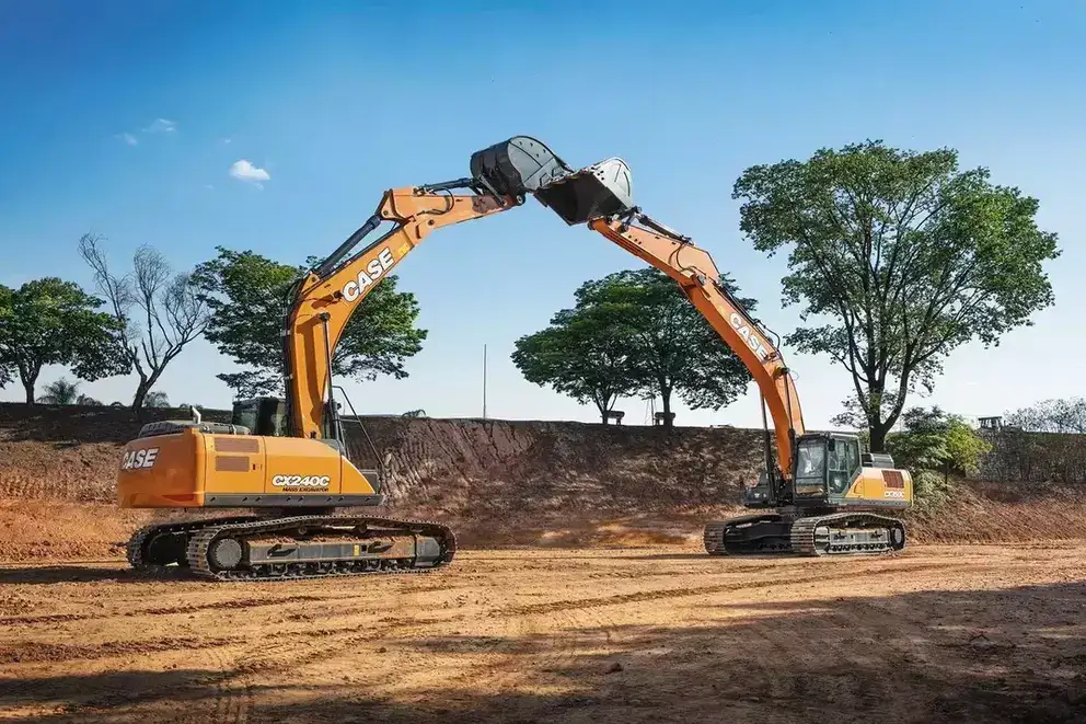 foto ao ar livre de duas escavadeiras hidráulicas da Case Construction. Elas formam um arco ao tocar suas pás no alto.
