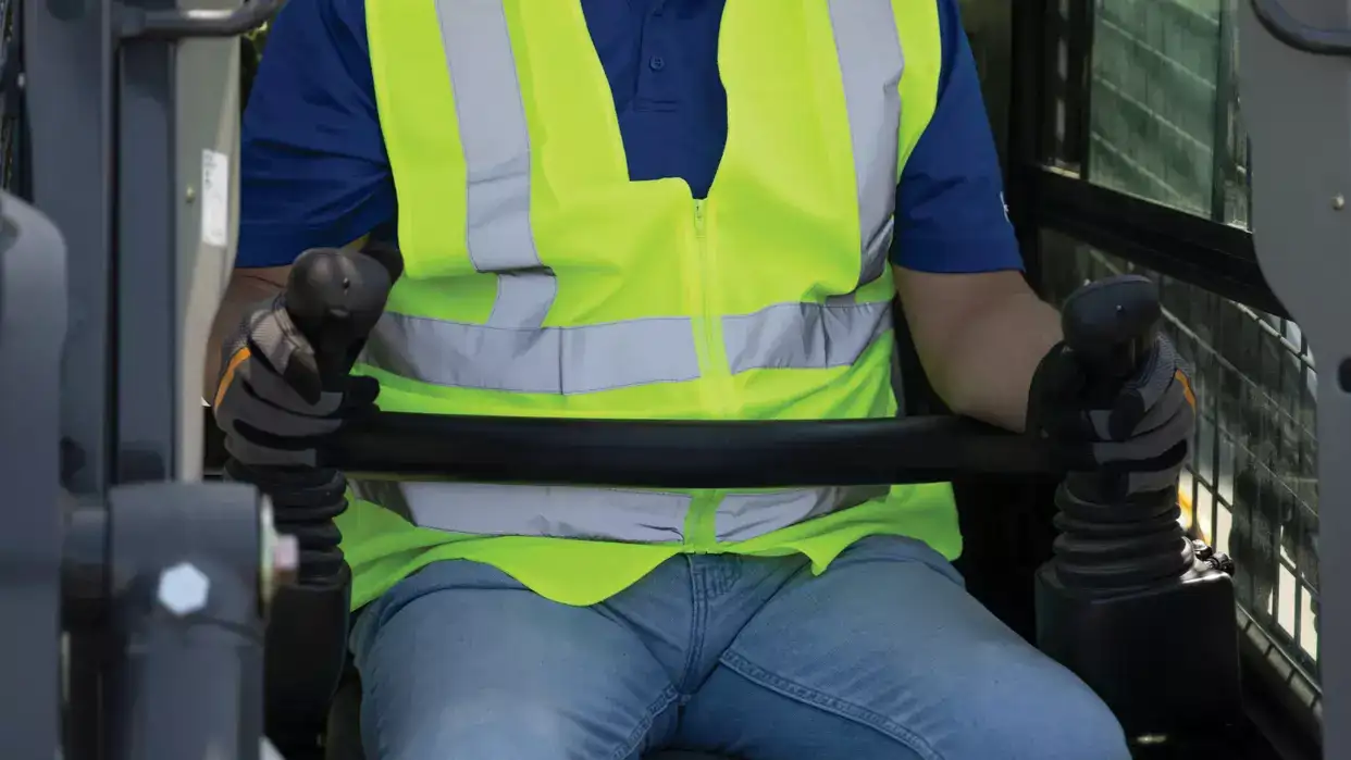 foto no interior da cabine da minicarregadeira New Holland Construction com um homem operando a máquina. 