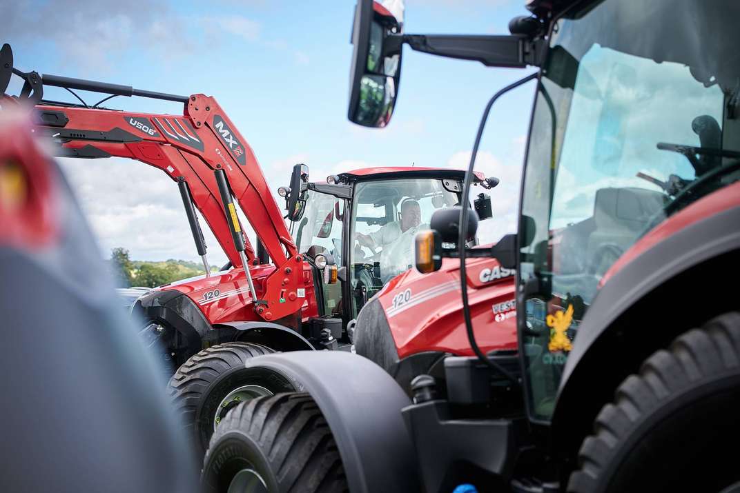 Lineup of red Case IH tractors with front loaders at Cowdray Park Polo Club.