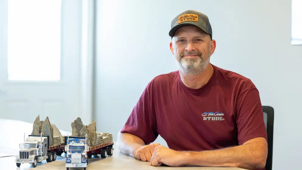 Man sitting at desk with toy trucks next to him.