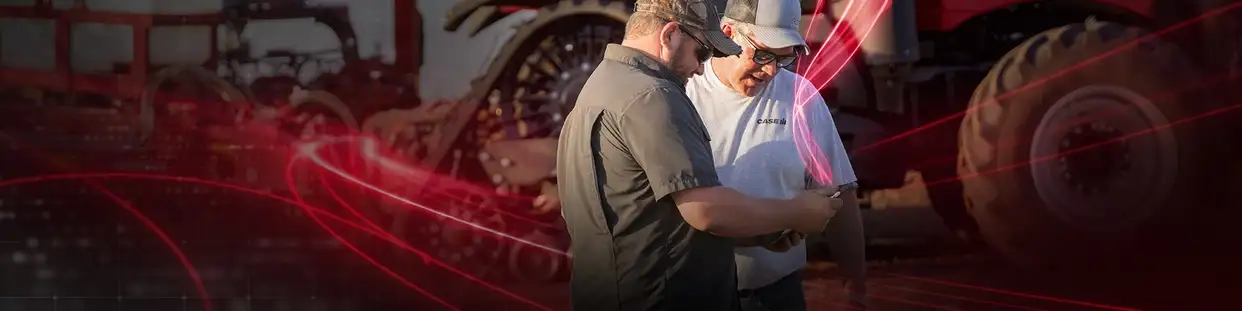 Two men stand closely examining a tablet, in front of a large tractor in the background. Red digital lines overlay the image, suggesting technology integration.