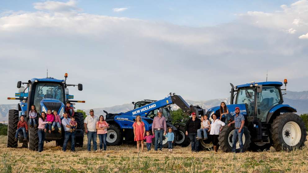 Family with T7 tractors and a TH7 telehandler in a field.