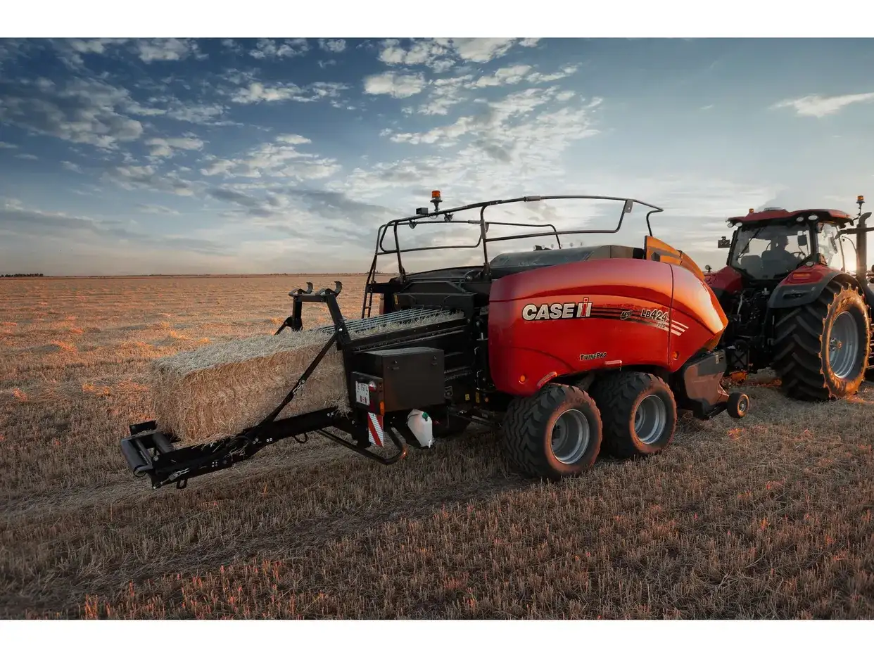 Case IH LB424 XL large square baler ejecting a straw bale in a stubble field at dusk