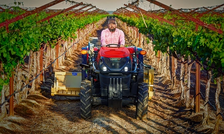 Man operating Farmall 120N tractor.