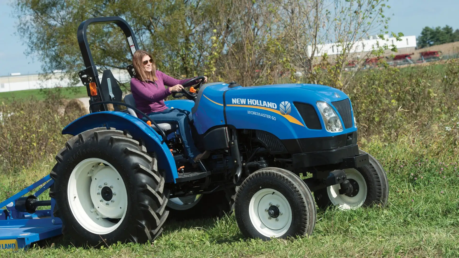 Woman operates WORKMASTER tractor with a mowing implement