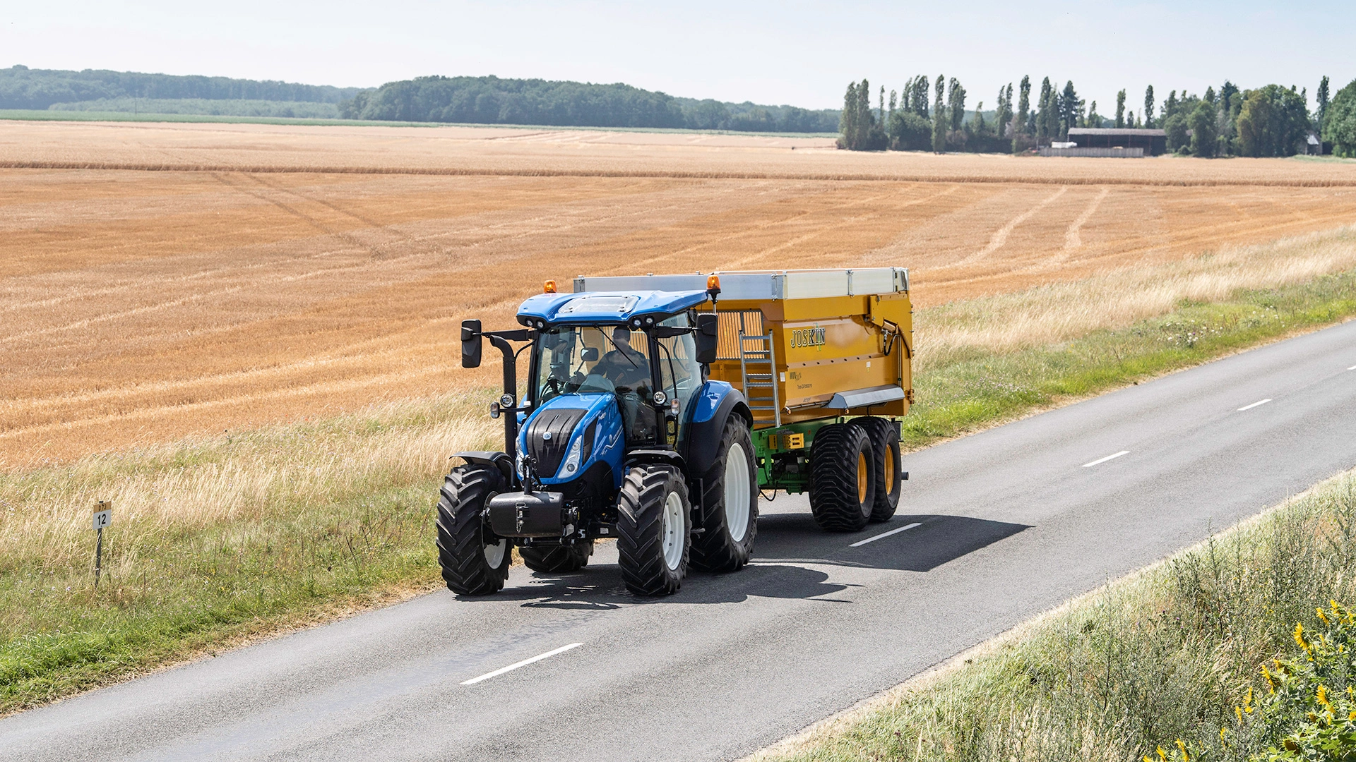 New Holland T5 Dynamic Command & Auto Command tractor in motion, transporting agricultural supplies