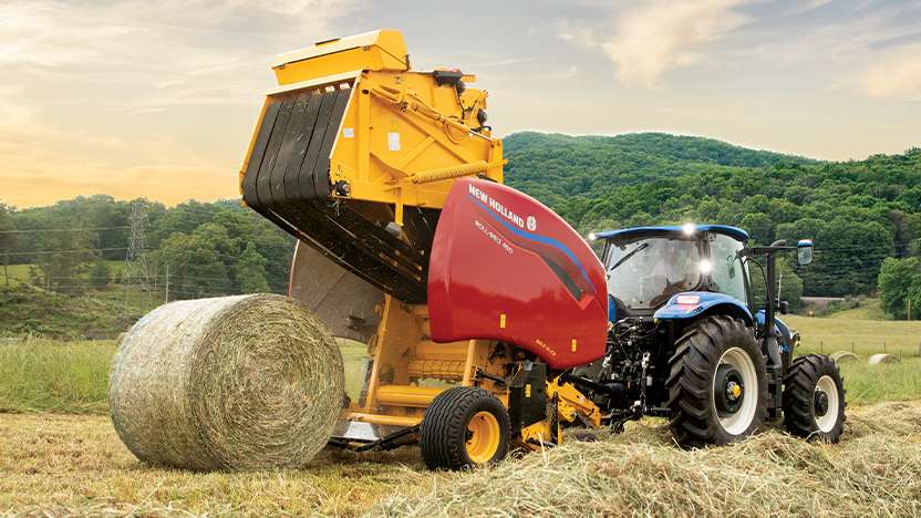 New Holland tractor pulls a baler while making hay.