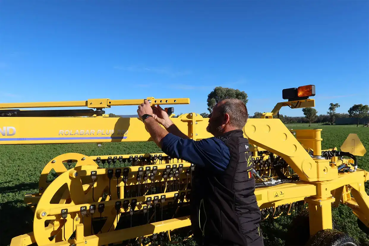 New Holland rolabar rake, roller bar working in field with New Holland tractor in Australia