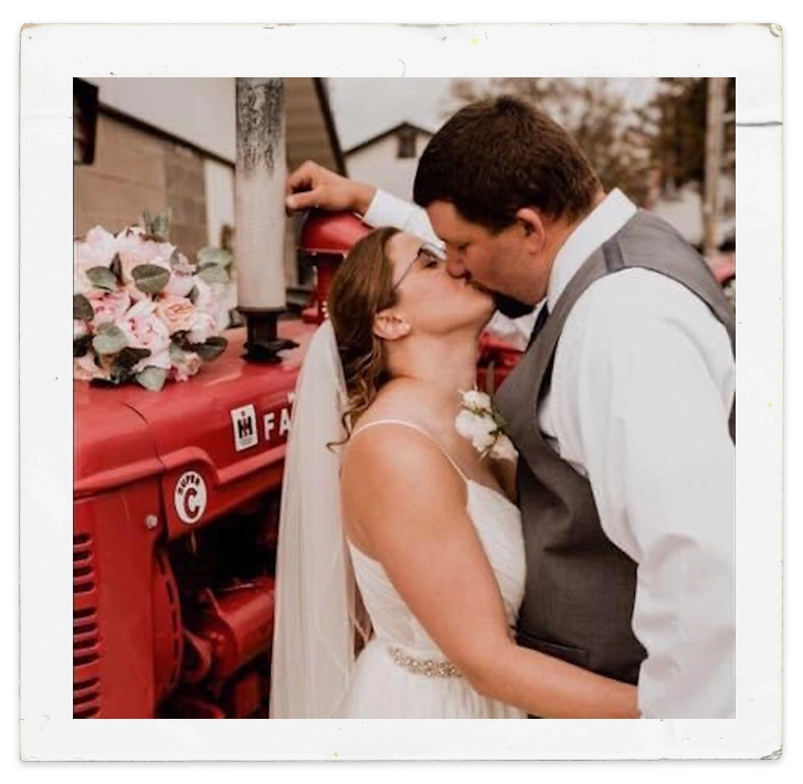 Cody K kissing his new wife in front of a vintage Farmall tractor