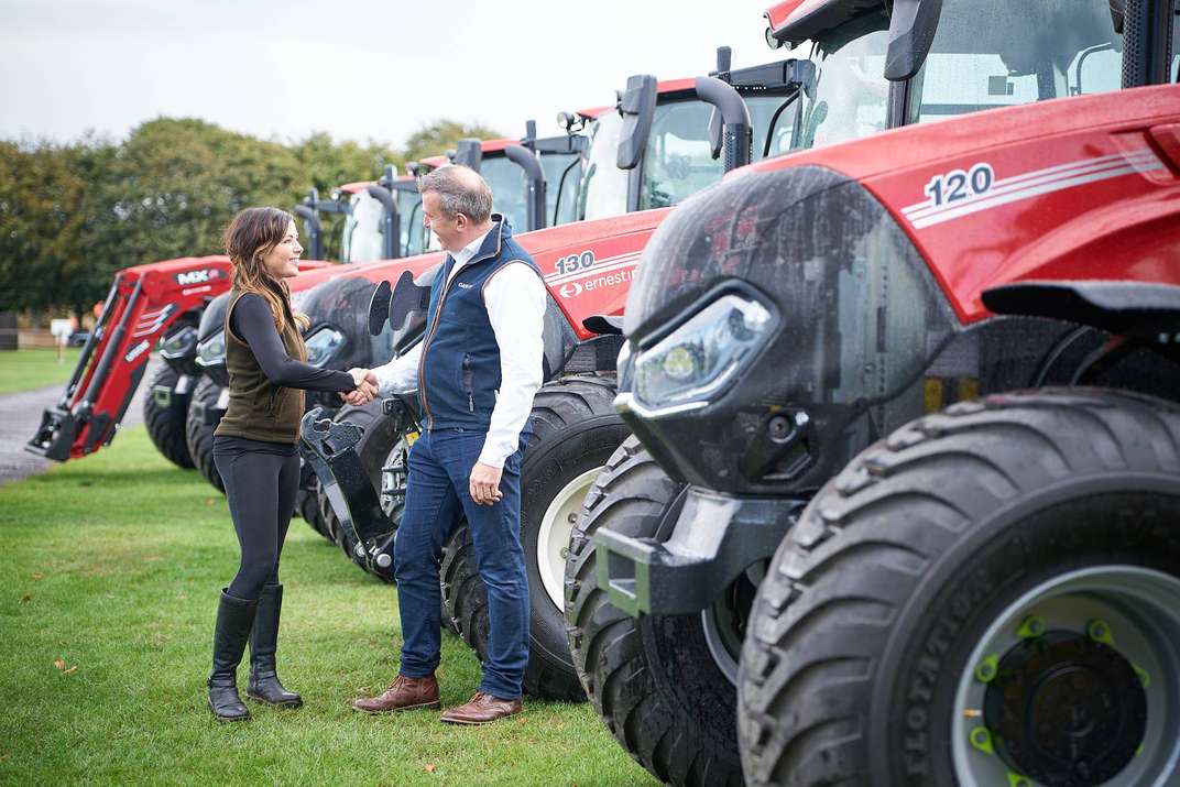 Representatives shaking hands in front of Case IH tractors at Cowdray Park Polo Club.