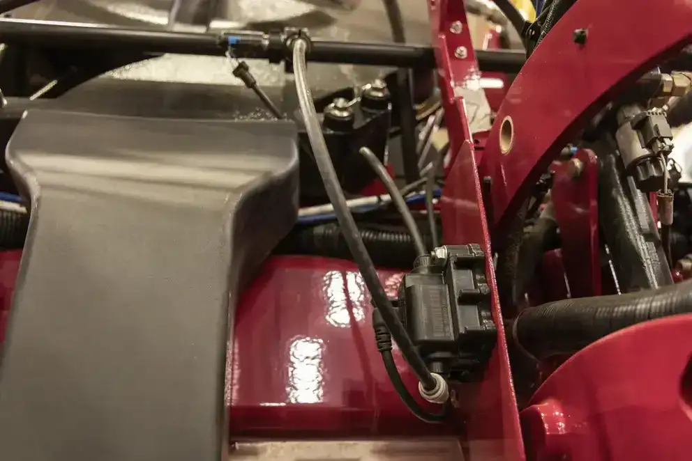 Close-up of a red Case IH engine compartment featuring black hoses, wires, and connectors. The mechanical components convey a sense of complexity and precision.